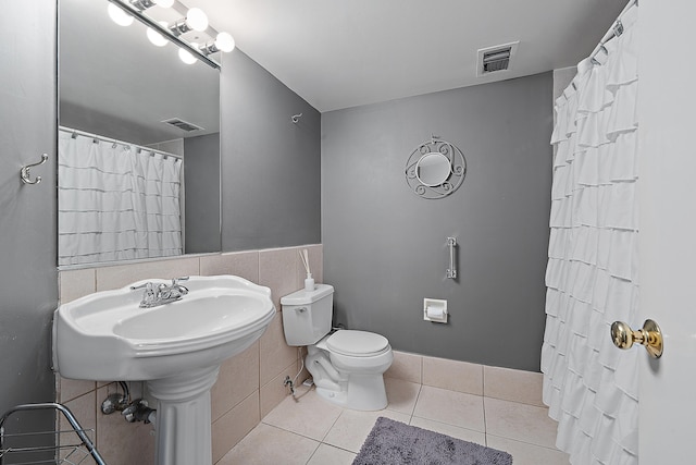 bathroom featuring tile walls, tile patterned floors, and toilet