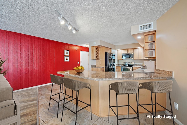 kitchen featuring rail lighting, a breakfast bar, kitchen peninsula, and appliances with stainless steel finishes