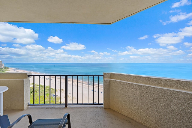 balcony with a water view and a view of the beach