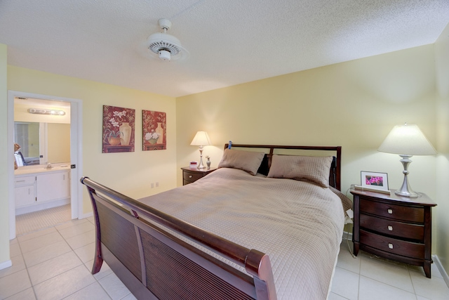 bedroom with ensuite bath, a textured ceiling, and light tile patterned flooring