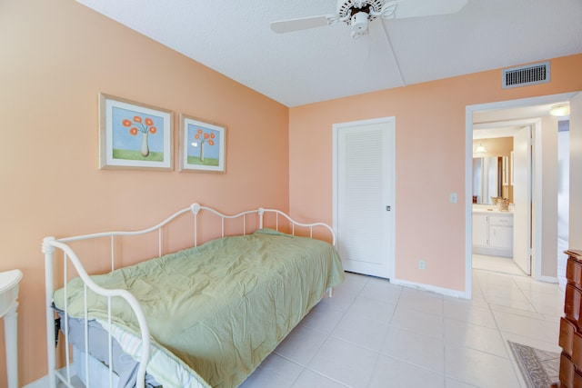 tiled bedroom with a closet, a textured ceiling, ensuite bathroom, and ceiling fan