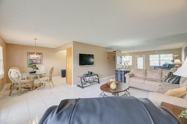 living room featuring a textured ceiling, light tile patterned flooring, and an inviting chandelier