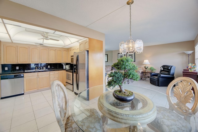 dining space with sink, ceiling fan with notable chandelier, and light tile patterned floors