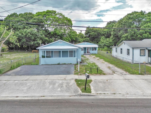 view of front of home with driveway, a fenced front yard, and a front lawn
