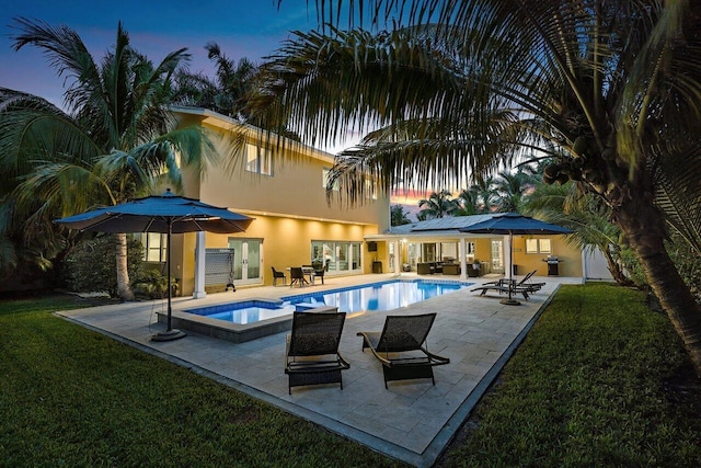 pool at dusk with a yard and a patio area