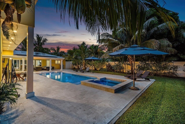 pool at dusk with an in ground hot tub, a yard, and a patio area