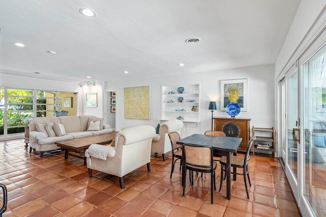 tiled living room featuring built in shelves and a textured ceiling