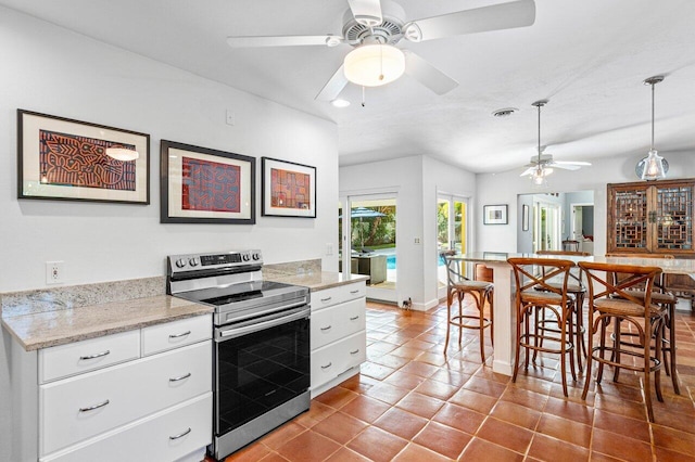 kitchen featuring light stone countertops, white cabinetry, electric range, and decorative light fixtures