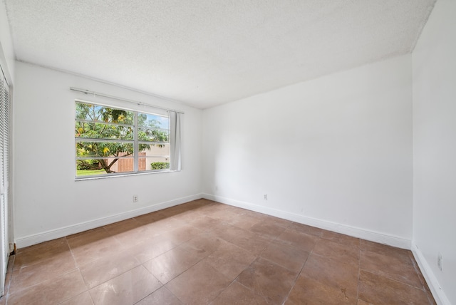 spare room with a textured ceiling and light tile patterned floors