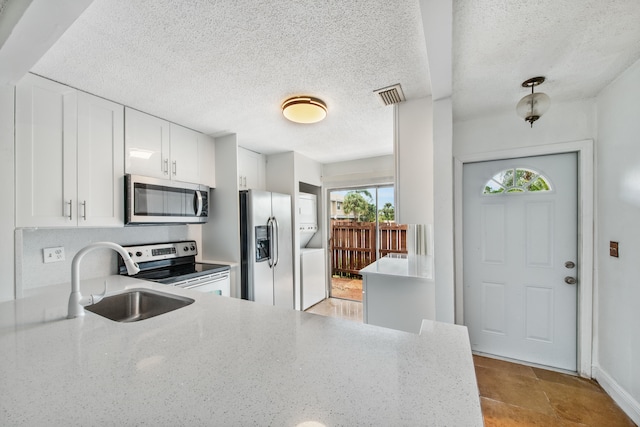 kitchen featuring light stone counters, appliances with stainless steel finishes, a textured ceiling, sink, and white cabinets