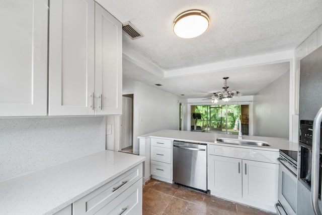 kitchen featuring stainless steel appliances, sink, kitchen peninsula, a textured ceiling, and white cabinets