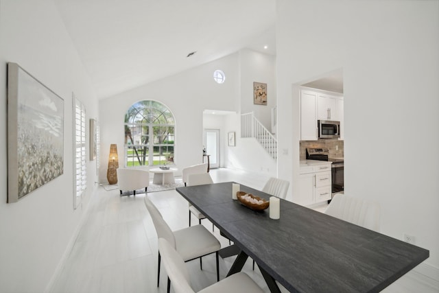 dining space with light tile patterned floors and high vaulted ceiling