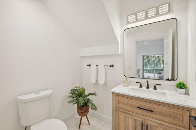 bathroom with vanity, toilet, and vaulted ceiling