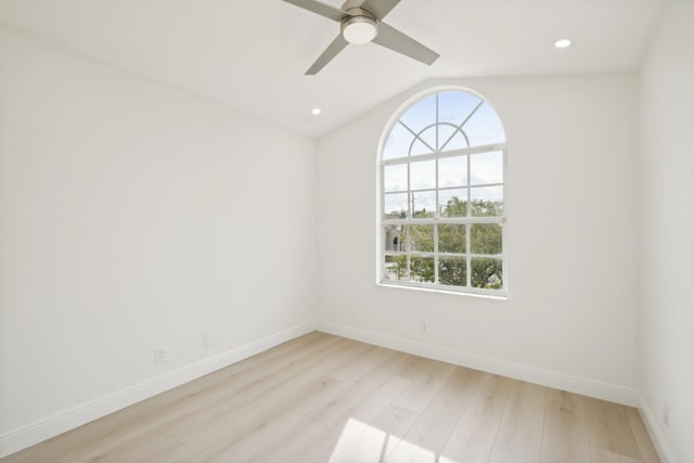 spare room featuring light hardwood / wood-style flooring, vaulted ceiling, and ceiling fan