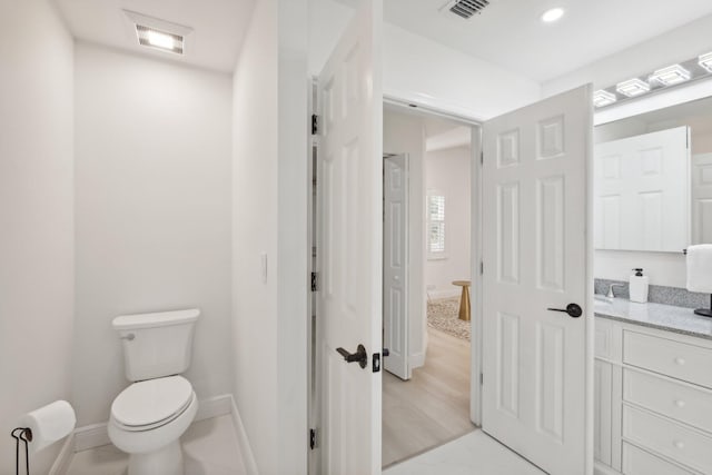 bathroom with hardwood / wood-style flooring, vanity, and toilet