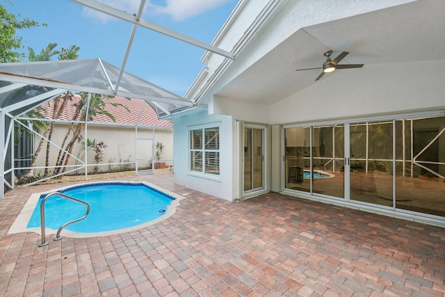 view of swimming pool featuring ceiling fan, glass enclosure, and a patio