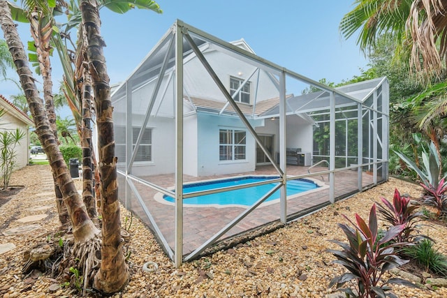 view of pool featuring glass enclosure and a patio area