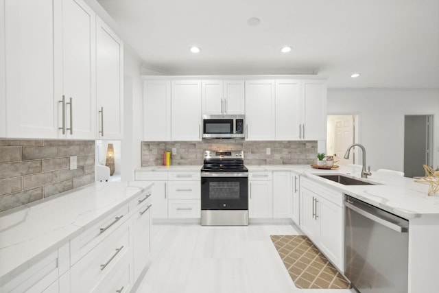 kitchen featuring white cabinets, sink, backsplash, appliances with stainless steel finishes, and light stone countertops