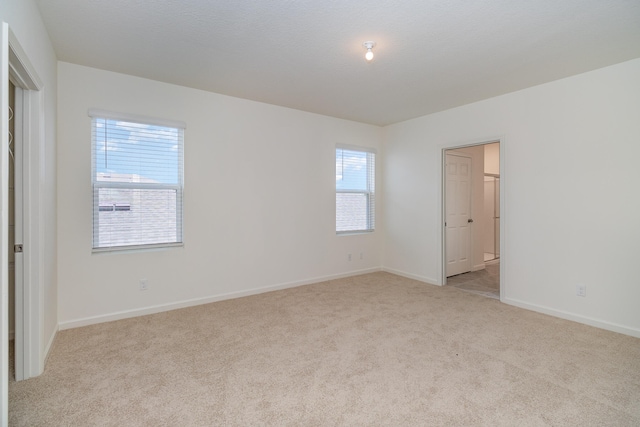 unfurnished bedroom featuring light colored carpet and multiple windows