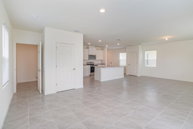 unfurnished living room with light tile patterned flooring and sink