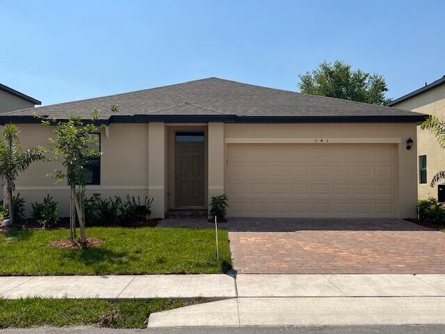 ranch-style home featuring a front yard, roof with shingles, stucco siding, a garage, and decorative driveway