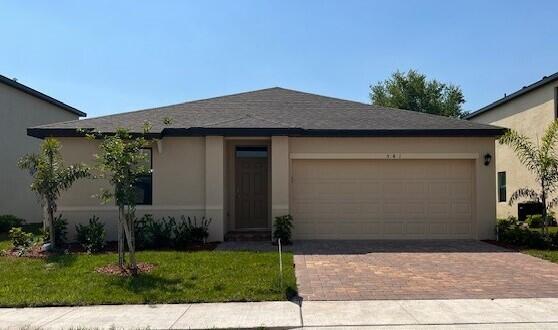 view of front of home with a front yard, decorative driveway, a garage, and stucco siding