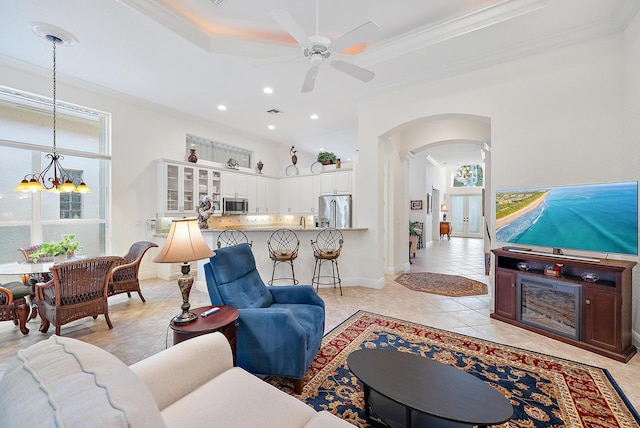 tiled living room with crown molding and ceiling fan with notable chandelier