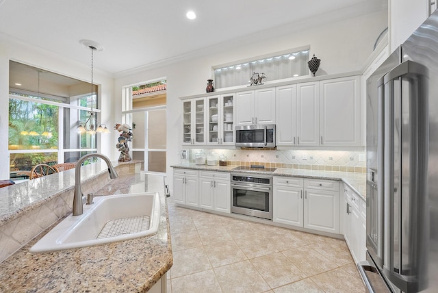 kitchen with pendant lighting, sink, white cabinetry, stainless steel appliances, and crown molding