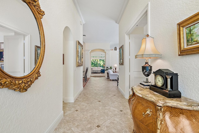 corridor featuring crown molding, a wealth of natural light, light tile patterned floors, and ornate columns