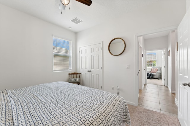 bedroom featuring ceiling fan, light tile patterned flooring, and a closet