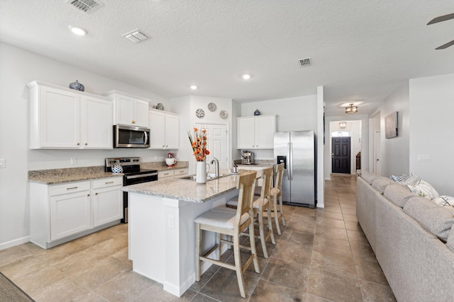 kitchen featuring white cabinets, a center island with sink, sink, a breakfast bar area, and stainless steel appliances