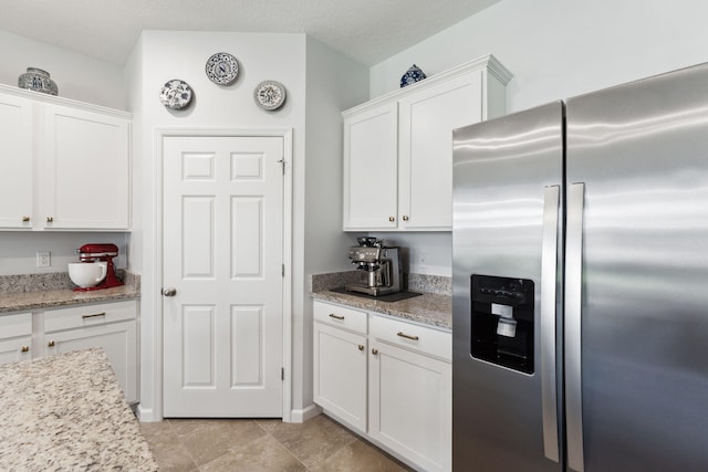 kitchen featuring white cabinets, stainless steel refrigerator with ice dispenser, and light stone counters