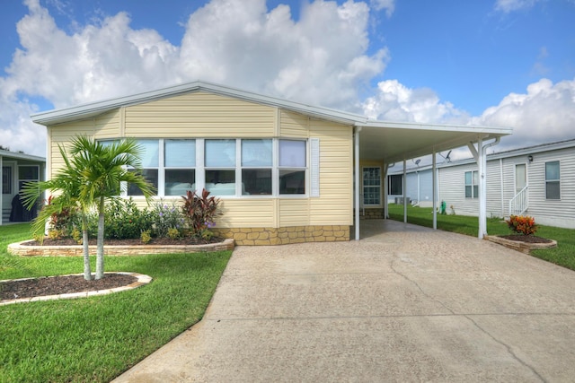 manufactured / mobile home with a front lawn and a carport