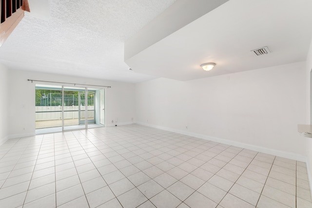 tiled empty room featuring a textured ceiling