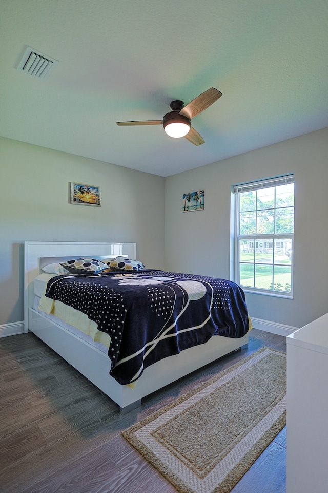 bedroom with dark hardwood / wood-style floors and ceiling fan