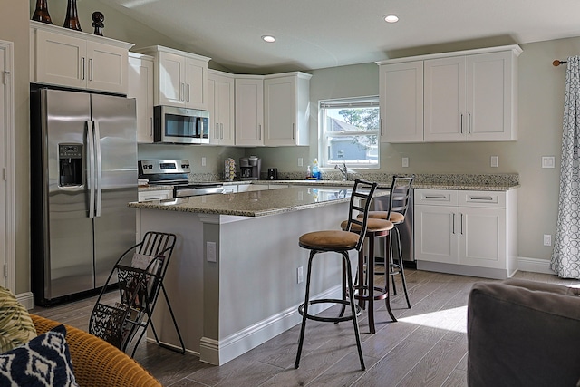 kitchen featuring light stone counters, white cabinets, appliances with stainless steel finishes, and light hardwood / wood-style floors