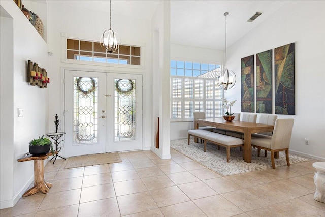 tiled foyer entrance featuring an inviting chandelier, french doors, and high vaulted ceiling