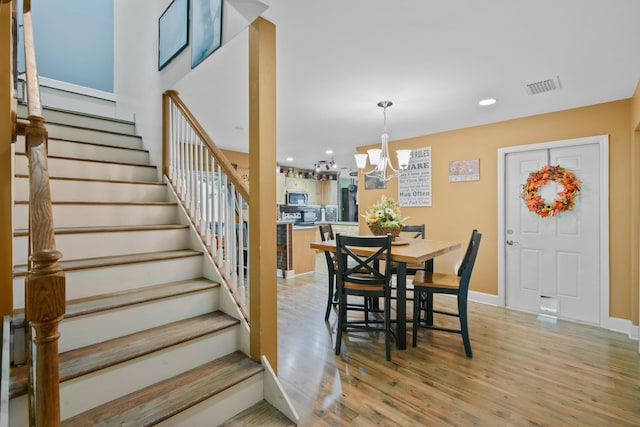 dining area with light wood-type flooring and an inviting chandelier