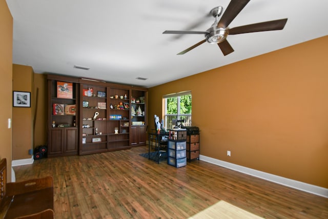 unfurnished office with dark hardwood / wood-style floors and ceiling fan