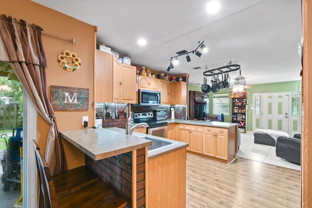 kitchen featuring light brown cabinets, appliances with stainless steel finishes, kitchen peninsula, and tasteful backsplash