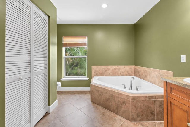 bathroom featuring toilet, tile patterned floors, tiled bath, and vanity