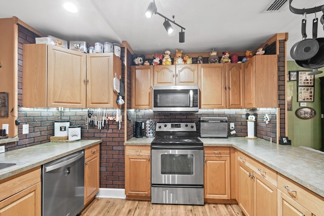 kitchen featuring decorative backsplash, appliances with stainless steel finishes, light brown cabinetry, and light hardwood / wood-style floors