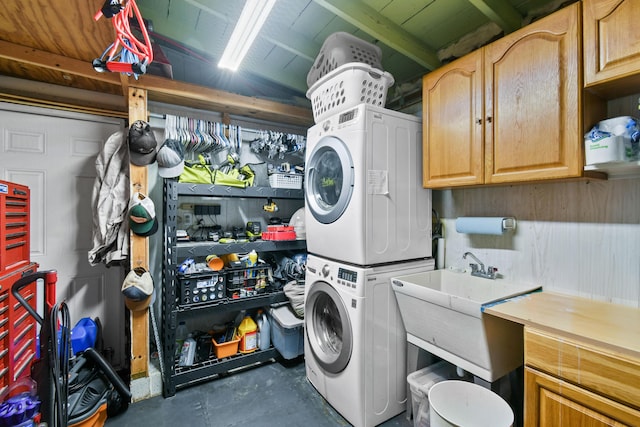 laundry area featuring stacked washer / dryer, cabinets, and a workshop area