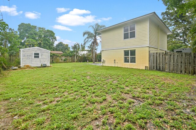 rear view of house featuring a wooden deck, a shed, and a yard