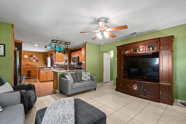 living room featuring ceiling fan, sink, and light tile patterned floors