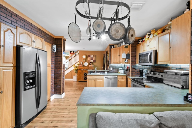 kitchen with backsplash, light brown cabinets, kitchen peninsula, and appliances with stainless steel finishes