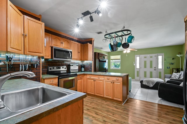 kitchen with sink, ceiling fan, appliances with stainless steel finishes, decorative backsplash, and kitchen peninsula