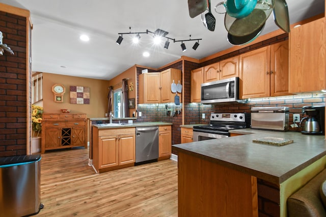 kitchen featuring sink, tasteful backsplash, light hardwood / wood-style flooring, appliances with stainless steel finishes, and kitchen peninsula