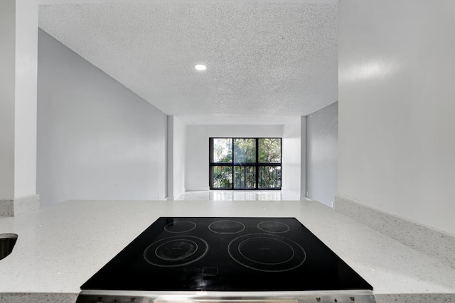 kitchen featuring light stone countertops, black range, and a textured ceiling