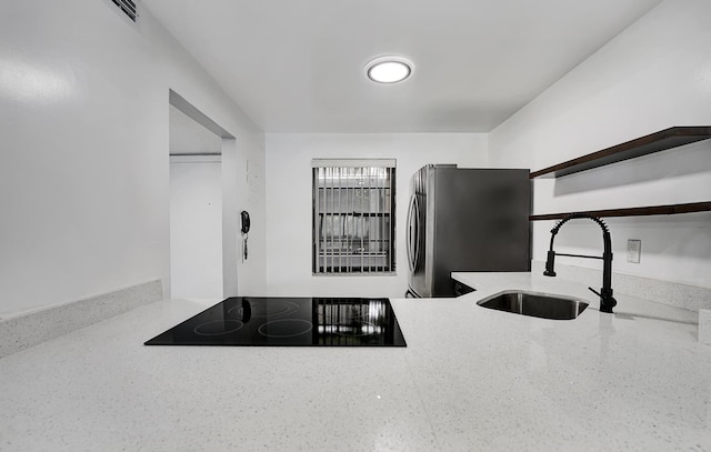 kitchen with black electric stovetop, stainless steel refrigerator, and sink